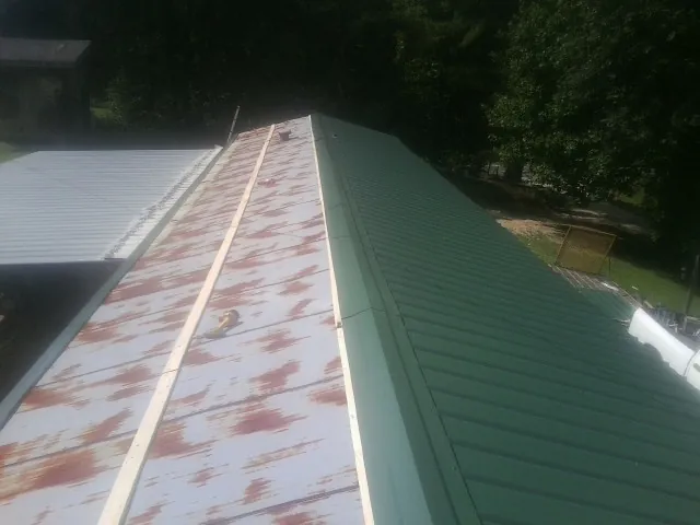 Old rusted panels beside newly installed green metal roofing — Wind Damage Roof Repair by Roofing Brothers in Gallatin