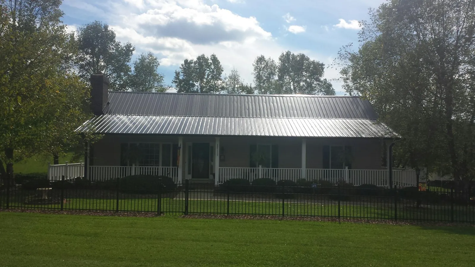 Gray metal roof on a brick ranch with a full width front porch — Gutter Guard Installation work by our crew in Gallatin
